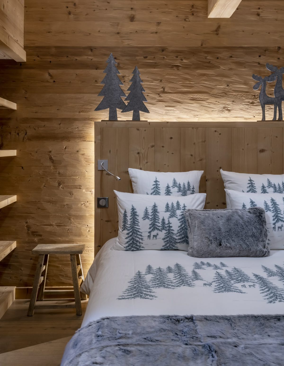Camera in stile chalet con arredi in legno e biancheria con motivo foresta — esempio upgrade Premium